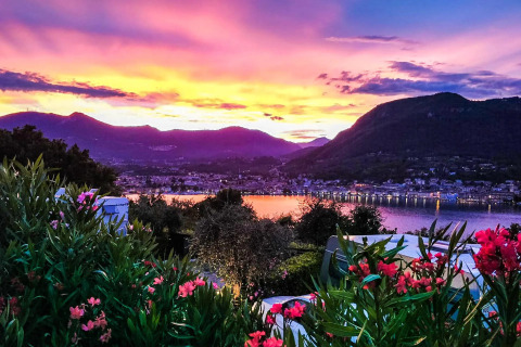 Bunter Sonnenuntergang mit Blick auf See, Berge und Blumen beim Weekend Glamping Resort in Lombardei, Italien.