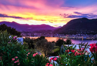 Bunter Sonnenuntergang mit Blick auf See, Berge und Blumen beim Weekend Glamping Resort in Lombardei, Italien.