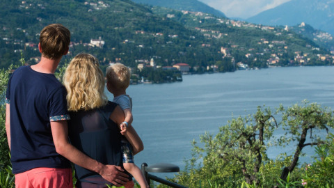Eine Familie blickt gemeinsam auf einen See und Berge im Weekend Glamping Resort, Lombardei, Italien.