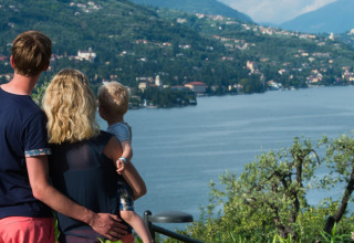 Eine Familie blickt gemeinsam auf einen See und Berge im Weekend Glamping Resort, Lombardei, Italien.