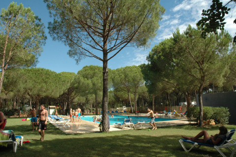 Vakantiegangers relaxen bij een zwembad tussen de pijnbomen in Wecamp L'Escala Punta Mila, Catalonië, Spanje.