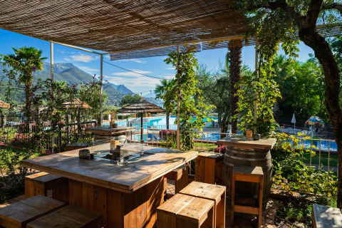 Gemütlicher Essbereich im Freien mit Holz- und Fassmöbeln am Pool im Weekend Glamping Resort, Lombardei.