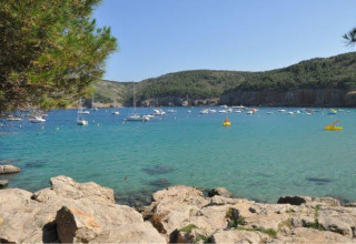 Vista dalle rocce del villaggio Wecamp L'Escala Punta Mila in Catalogna, Spagna, con barche nel mare azzurro.