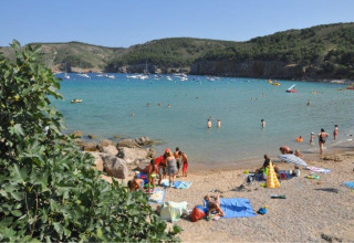 Vakantiegangers genieten van het strand en zwemmen in zee bij Wecamp L'Escala Punta Mila, Catalonië, Spanje.