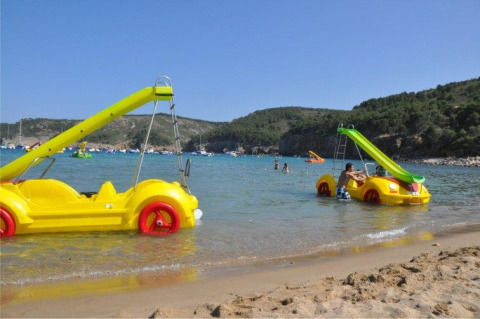 Gele waterfietsen in de vorm van auto's met glijbanen op het strand van Wecamp L'Escala Punta Mila, Catalonië.