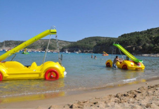 Pedalò gialli a forma di auto con scivolo sulla spiaggia di Wecamp L'Escala Punta Mila, Catalogna, Spagna.