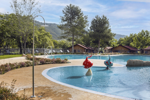Buitenzwembad met paddenstoelsculpturen, ligstoelen en huisjes bij Wecamp Pirineos in Aragón, Spanje.