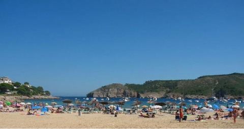 Strandbild im Wecamp L'Escala Punta Mila, Katalonien, Spanien, mit Badegästen, Sonnenschirmen und Booten.