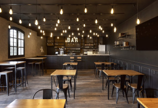Moderne Bar mit stilvoller Beleuchtung und Holzmöbeln im Wecamp Pirineos in Aragón, Spanien.