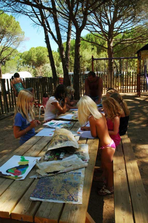 Børn deltager i en udendørs maleworkshop under træerne på Wecamp L'Escala Punta Mila i Catalonien.