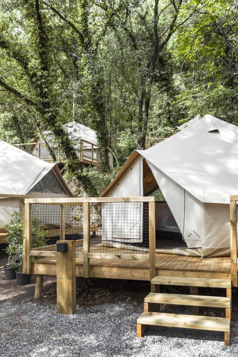Glampingzelte auf Holzterrassen im Grünen, aufgenommen im Wecamp Pirineos Ferienpark in Aragón, Spanien.