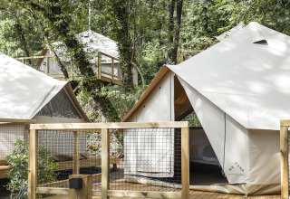 Glampingtelte på trædæk omgivet af grønne træer i Wecamp Pirineos feriepark i Aragón, Spanien.