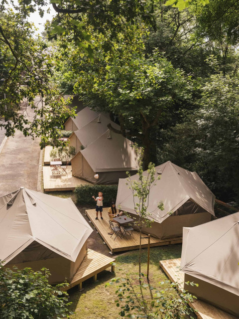 Tentes de luxe à Wecamp San Sebastián, un parc de vacances au Pays basque, entourées d'arbres verdoyants.