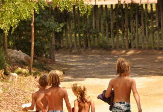 Vier kinderen in zwemkleding lopen richting het zwembad bij Wecamp L'Escala Punta Mila, een vakantiepark in Catalonië.