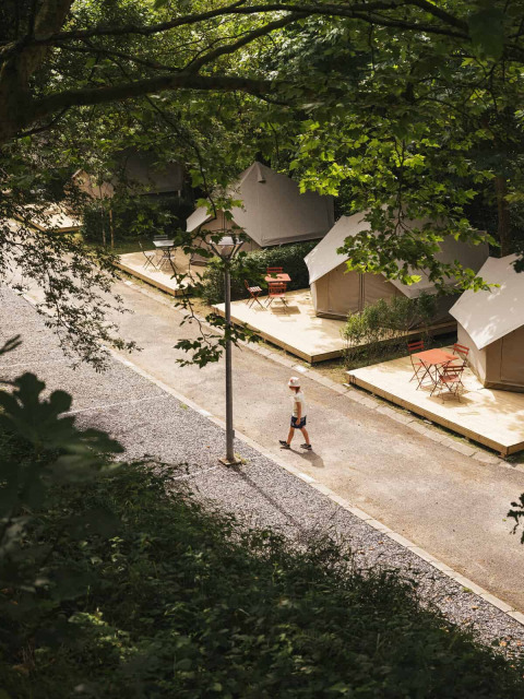 Luftfoto af glamping telte og gående dreng på Wecamp San Sebastián i Baskerlandet, Spanien, om sommeren.