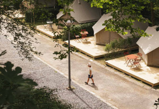 Vista aérea de tiendas glamping y un niño caminando en Wecamp San Sebastián, parque vacacional en País Vasco, España.