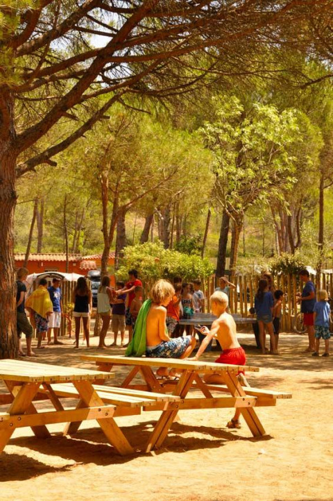 Kinderen spelen en zitten op picknickbanken bij Wecamp L'Escala Punta Mila, een vakantiepark in Catalonië.