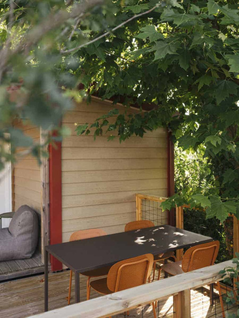 Outdoor patio at Wecamp San Sebastián featuring a dining table, chairs, and leafy trees in Basque Country, Spain.