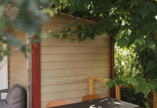 Buitenterras bij Wecamp San Sebastián met eettafel, stoelen en groene bomen in Baskenland, Spanje.
