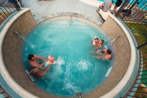 Ovenfra billede af familier, der nyder en rund swimmingpool på Weekend Glamping Resort i Lombardiet, Italien.