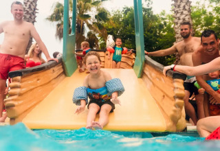 Smiling child with floaties slides into pool surrounded by adults at Weekend Glamping Resort in Lombardy, Italy.