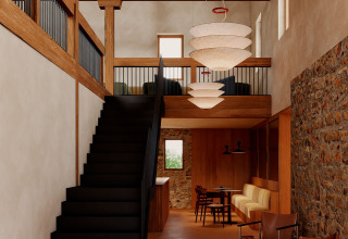 Modern interior with wooden beams, stone wall, and black staircase at Wecamp San Sebastián, Basque Country, Spain.