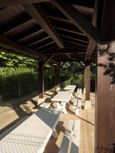 Overdekte buitenruimte met witte tafels en banken bij Wecamp San Sebastián, Baskenland, Spanje.