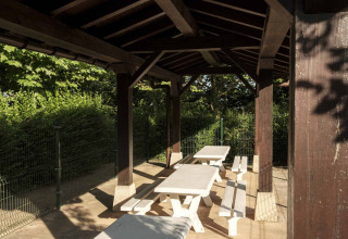 Überdachter Außenbereich mit weißen Tischen und Bänken im Wecamp San Sebastián, Baskenland, Spanien.