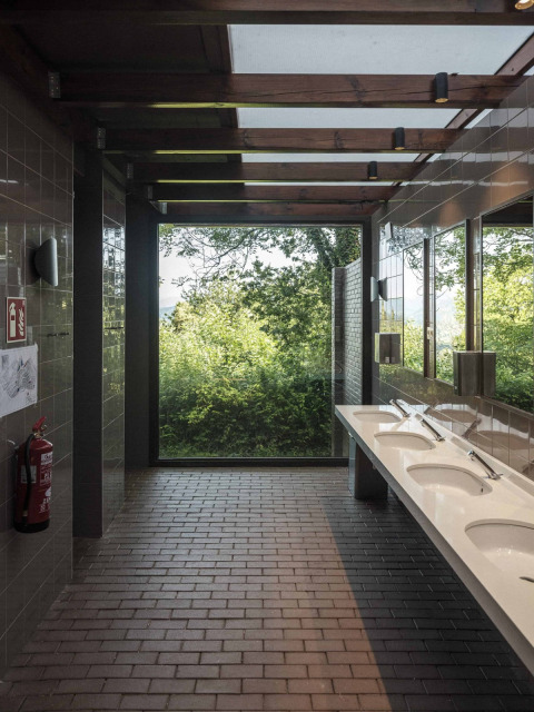 Baño moderno con grandes ventanales y vistas a la naturaleza en Wecamp San Sebastián, País Vasco, España.