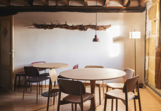 Indbydende spiseområde med træmøbler og moderne loft, fremhævet i Wecamp San Sebastián, Baskerlandet.