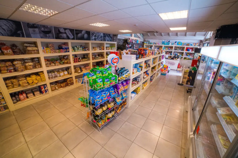 Innenaufnahme eines kleinen Supermarkts im Weekend Glamping Resort in der Lombardei, Italien, mit Snacks und Regalen.