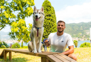 Man in a white t-shirt and his husky enjoying a sunny outdoor day at Weekend Glamping Resort, Lombardy, Italy.