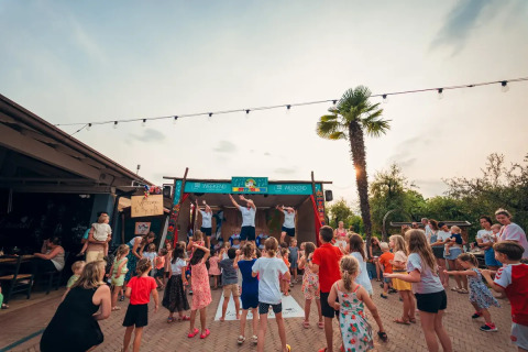 Kinder tanzen und spielen im Freien bei Weekend Glamping Resort in Lombardei, Italien, am Abend.