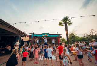 Children dancing and playing outdoors at Weekend Glamping Resort, Lombardy, Italy, in the evening light.