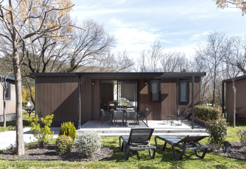 Casa móvil FAMILY XL lodge con terraza, muebles de exterior modernos, tumbonas y entorno ajardinado.