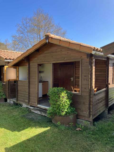 Gemütliche Holzhütte mit Veranda im Wecamp Cudillero Ferienpark in Asturien, Spanien, bei klarem Himmel.