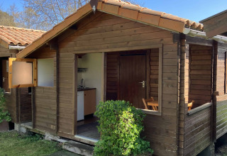 Gemütliche Holzhütte mit Veranda im Wecamp Cudillero Ferienpark in Asturien, Spanien, bei klarem Himmel.