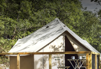 Tienda Safari Bell en el bosque, terraza de madera y mesa con tazas, ideal para una estancia relajante.