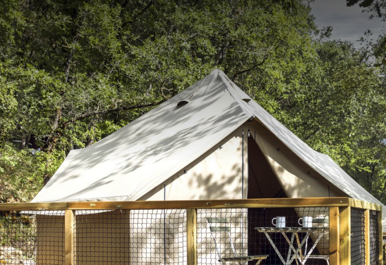 Safari-Bell-Zelt im Wald mit Holzterrasse, Tisch und zwei Tassen, ideal für entspannten Natururlaub.