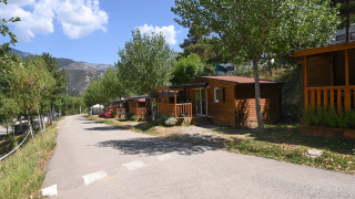 Udsigt over Mobile Home Basic Family lodge med træhytter, grønne træer og bjerge i baggrunden.