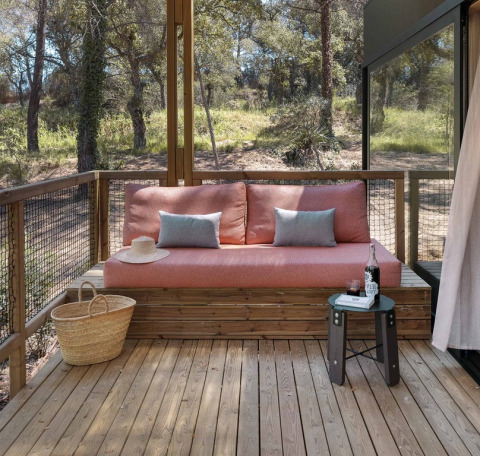 Træterrasse med pink sofa, blå puder og kurv på Mobile home 'Couple Plus' ved Wecamp San Sebastián i Spanien.
