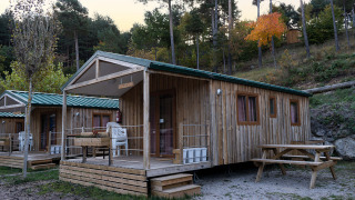 Houten chalets met veranda en picknicktafel bij Mobile Home Basic Family+ Panoramic, omgeven door natuur.