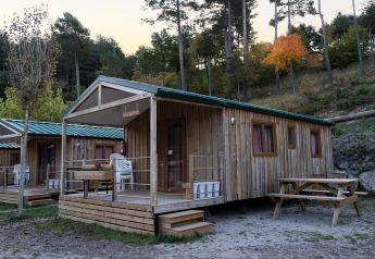 Træhytter med veranda og picnicbord ved Mobile Home Basic Family+ Panoramic, omgivet af skov og bakker.