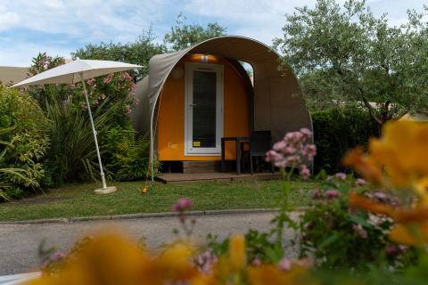 Tienda safari 'Coco Couple' en Weekend Glamping Resort, Italia, con sillas, mesa y sombrilla al frente.