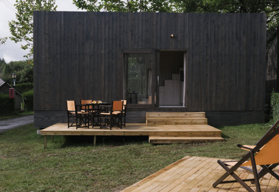 Tiny Home Family Wood, modern tiny house met houten terras, buitenzitje en een groene, rustige omgeving.