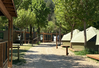 Pad tussen safaritenten en houten hutten bij Bell Tent op Wecamp Pedraforca, Spanje, omgeven door bomen.