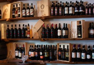Bouteilles de vin et caisses en bois sur étagères au Vallicella Glamping Resort en Toscane, Italie.