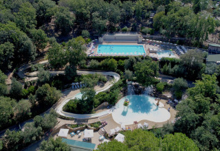 Vue aérienne du Vallicella Glamping Resort en Toscane, Italie, avec des piscines entourées de forêts.