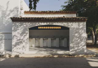 Buiten toiletruimte met zes wastafels bij Wecamp Jávea vakantiepark in Valencia, Spanje, onder schaduwrijke bomen.
