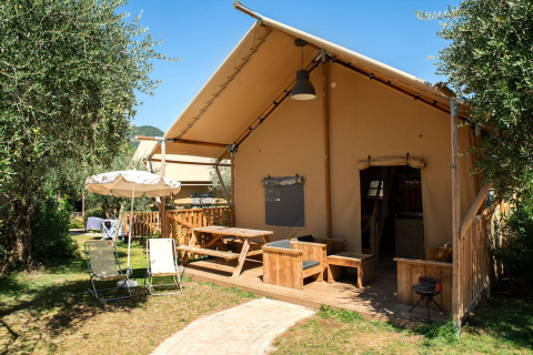 Safari Lodge safaritelte med træterrasse, havemøbler og parasol i et grønt udendørs område.